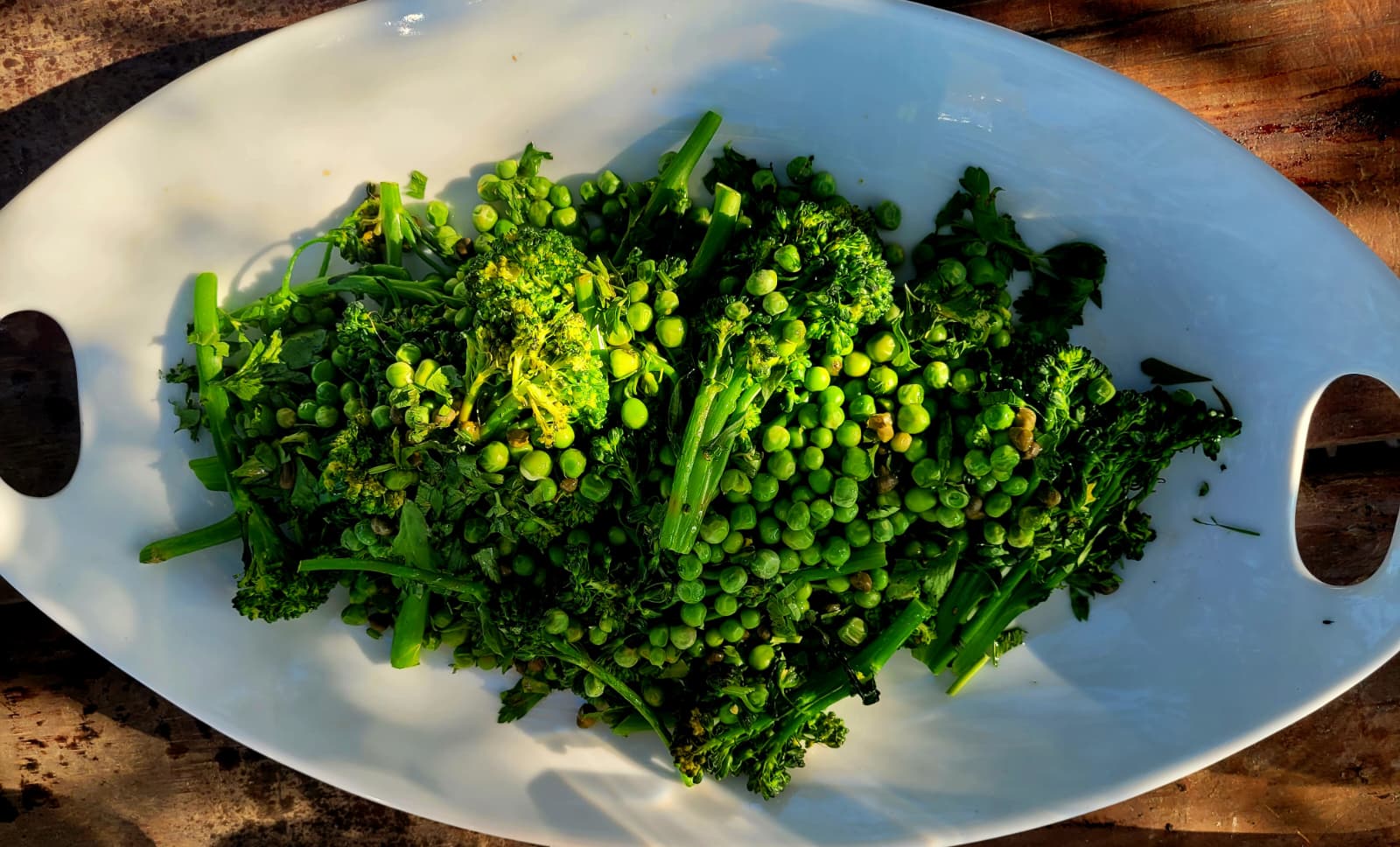 Broccolini, peas and herbs in a white dish
