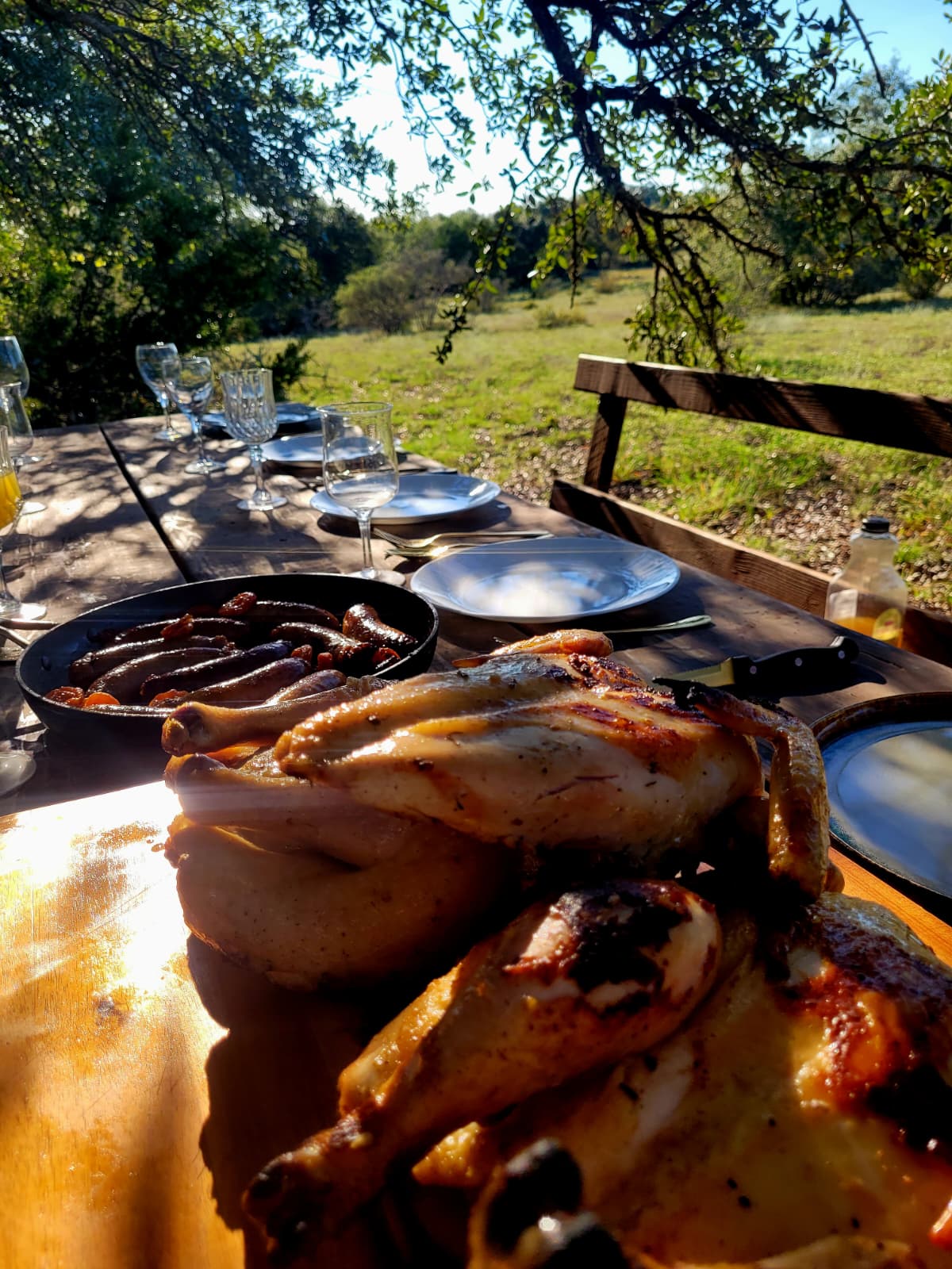 Roast chickens on the board with glasses of wine behind